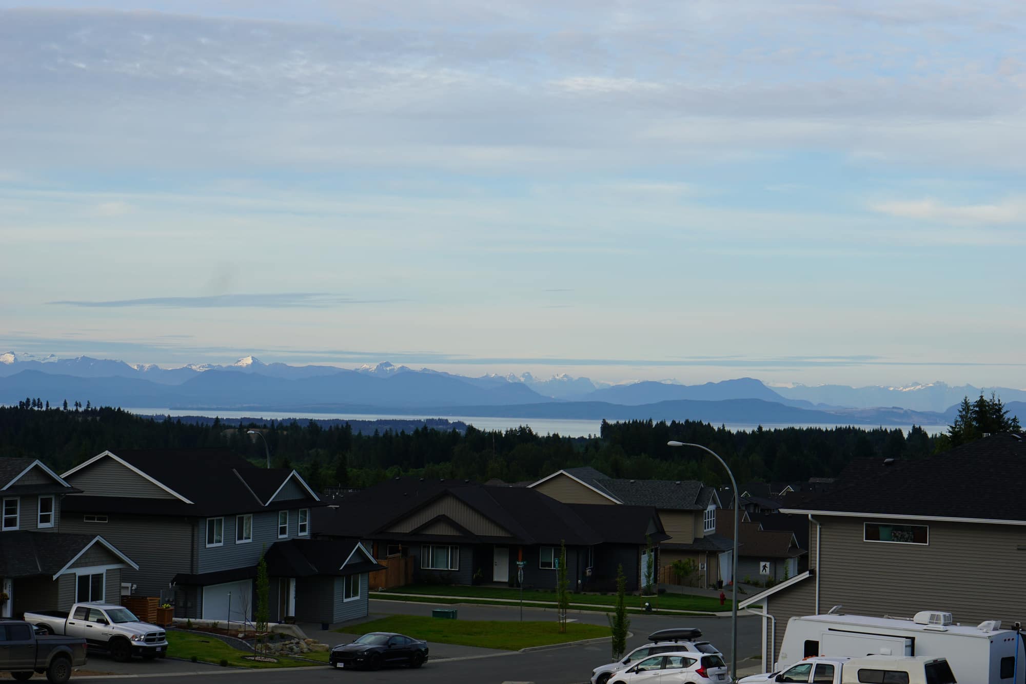 Homes on the Ridge above the treeline, with the ocean and the snow-capped Coast Mountains in the distance.